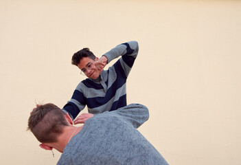 A young male bully aggressively punching another scared male