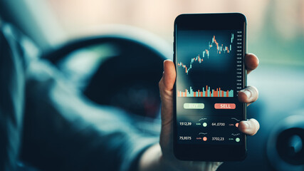 Woman showing mobile phone investing application in car. Stock market investment app in hand. Close-up view