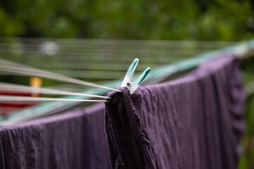 Eine Wäscheklammer klemmt an der Wäsche aufgehängt im Garten