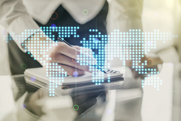 Double exposure of abstract digital world map and man hand writing in notepad on background, big data and blockchain concept