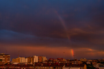 Rainbow in the city of Zaragoza after rain on a hot summer day due to high temperatures due to climate change, Spain