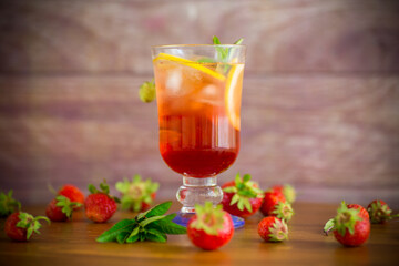 refreshing cool strawberry lemonade with lemon, ice and mint in a glass