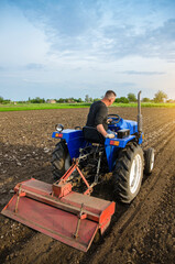 A farmer is cultivating a field before replanting seedlings. Milling soil. Softening the soil and...