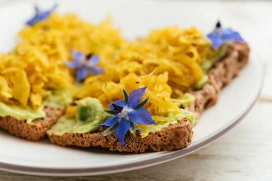 Home made avocado toasts with curried sauerkraut, garnished with boretch flowers.