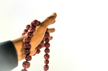 Image of Prayer beads in hand. Male hand holding rosary, praying to god on white background,...