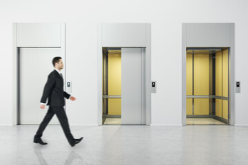 Fototapeta premium Businessman walking in white concrete interior with three elevator doors. Opportunity and success concept.