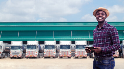 African male truck driver holding tablet and checking route for new destination. In background...