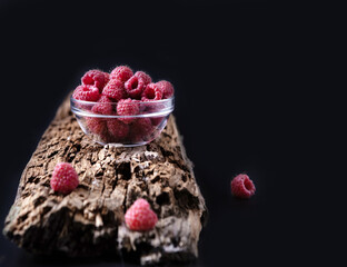 fresh raspberries in a glass cup on a wooden background