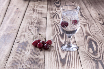 a glass of fresh seltzer water with a cherry on a wooden background