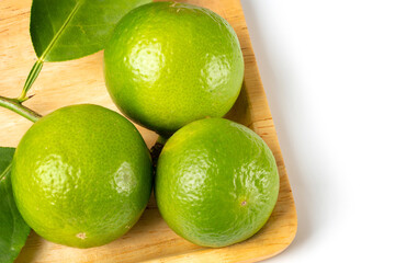 Close up natural fresh lime, green leaf, on wooden dish, white background.