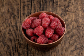 red fresh domestic raspberry at bowl on a rustic table top. space