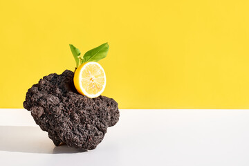 Fresh organic lemon on black volcanic stone. Minimal food creative concept on yellow pastel...