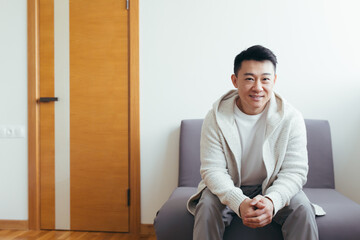 Young asian man got a good news sitting and smiling in the waiting room for interview results or...