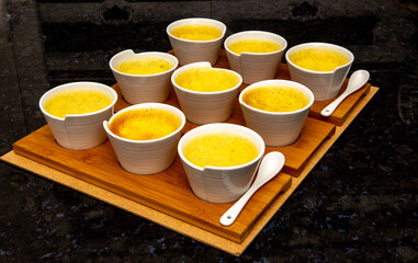 Typical Cream brulee , creme brulée, with natural vanilla beans in ramekins with spoons and lined up in depth of field blur