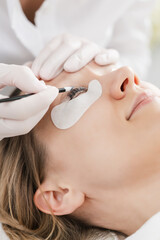 Cosmetician applying eyelash treatment to enhance the beauty of woman customer