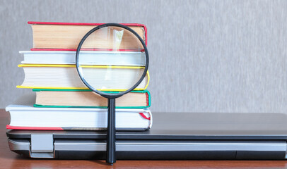 Books on laptop and magnifier.Education concept