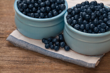 Summer blueberries in blue bowls on wooden table