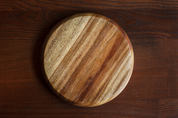 An empty, clean cutting board with a beautiful texture on a dark wooden table.