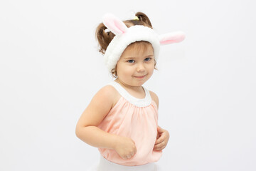 Charming girl in dress and white ears posing as cute bunny on gray background