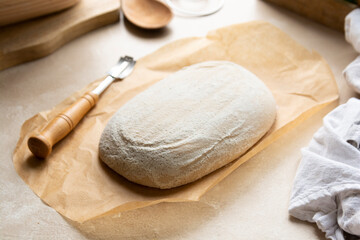 Sourdough bread loaf scoring in banneton, raw dough in proofing rattan basket, homemade bread made from wild yeast.