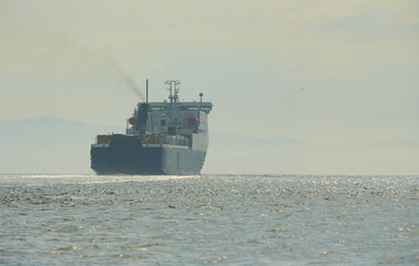 Huge container tanker ship carrying truck size colourful containers in deep blue open ocean sea