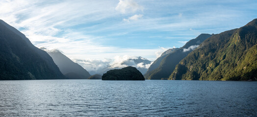 Sun rising over Doubtful Sound, Clouds hanging low on the mountains, Fiordland National Park, New...