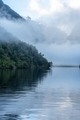 Naklejka premium A new morning dawning at Doutful Sound, clouds hanging low in the mountains, Fiordland National Park, New Zealand