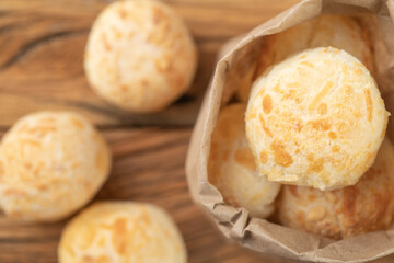 Typical brazilian cheese buns in a paper bag over wooden table