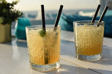 Two tasty fruit cocktails on a wooden table. Fruit Mojito on the beach. Beautiful glasses for cocktails