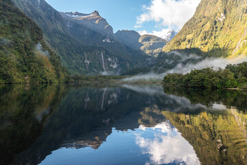 Fototapeta na wymiar A new morning dawning at Doutful Sound, clouds hanging low in the mountains, Fiordland National Park, New Zealand