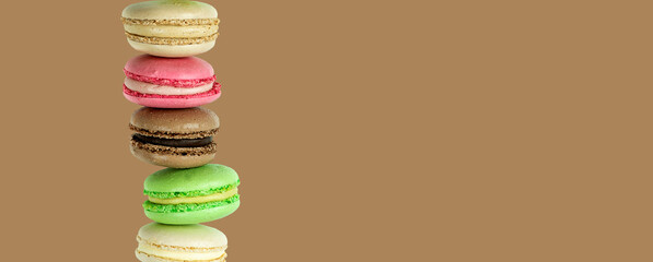 Stack of cake macarons on a chocolate brown background with copy space