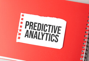 The word PREDICTIVE ANALYTICS on torn paper on red notepad,.