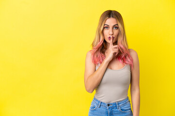 Young woman over isolated yellow background showing a sign of silence gesture putting finger in...