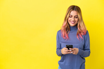 Fototapeta premium Young woman over isolated yellow background sending a message with the mobile