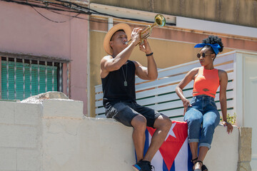 Latina woman watching a latino man playing a trumpet: Selective focus. Music and diversity concept.