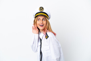 Airplane pilot over isolated white background listening to something by putting hand on the ear
