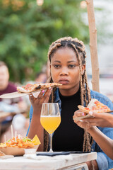 Afro american woman quietly holding a slice of pizza