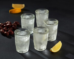 Icy shot glasses of vodka with lemon and olives