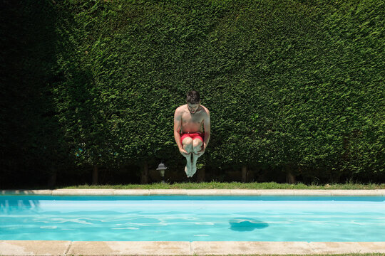 Young man jumping into a swimming pool. Summer concept.