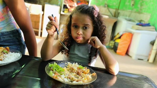 Brazilian little girl eating food. Hispanic child at lunch table