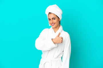 Young woman in a bathrobe over isolated blue background giving a thumbs up gesture