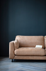 Comfortable sofa with pillows in the interior of a spacious living room, real photo with copy space on an empty black wall