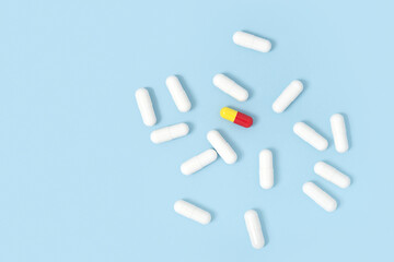 Scattered white pills capsules on blue table background. Medicine, pharmacy and healthcare concept. Copy space. Flat lay