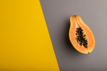 Ripe cut papaya on yellow and gray pastel background. Top view, copy space.