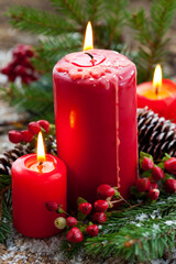 Christmas decoration with red candles, berries and pine cone