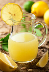 Fresh lemon juice in jug on wooden table