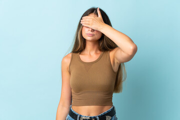 Young caucasian woman isolated on blue background covering eyes by hands. Do not want to see something