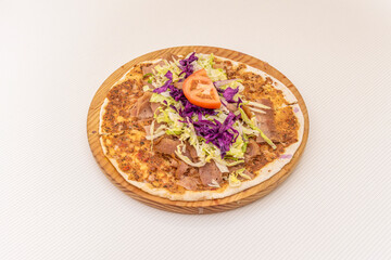 Arab kebab pizza, lahmacun with purple cabbage, tomato, grated iceberg lettuce on wooden plate.