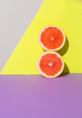 Two bright grapefruit slaces againt vibrant background. Trendy sunlight Summer concept