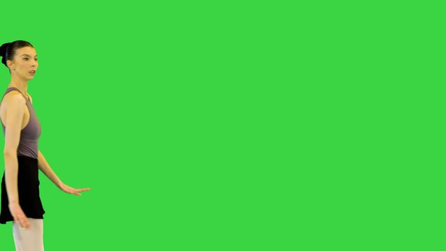 Young ballerina in training clothes exercises jump on a Green Screen, Chroma Key.